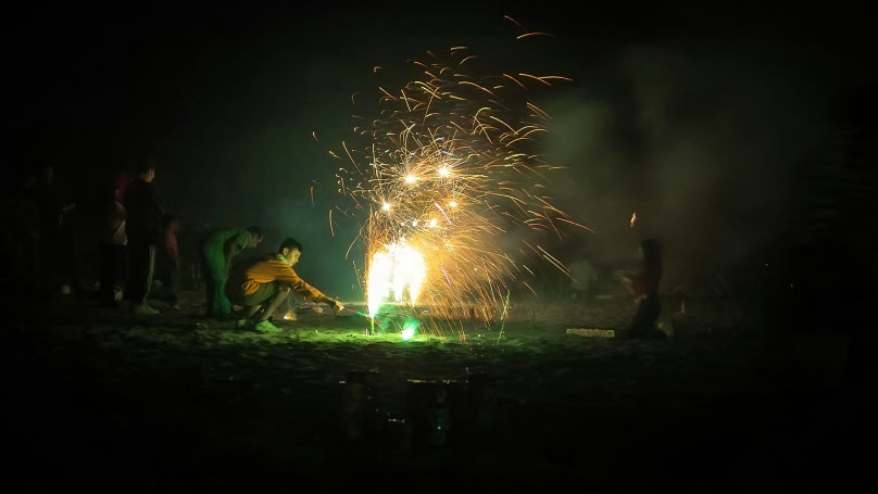 immagine di un uomo che accende fuochi d'artificio su una spiaggia