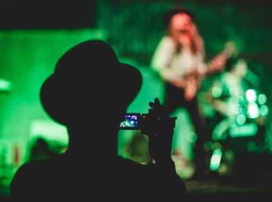 immagine della parte posteriore della testa di un uomo che registra un cantante dal vivo in lontananza