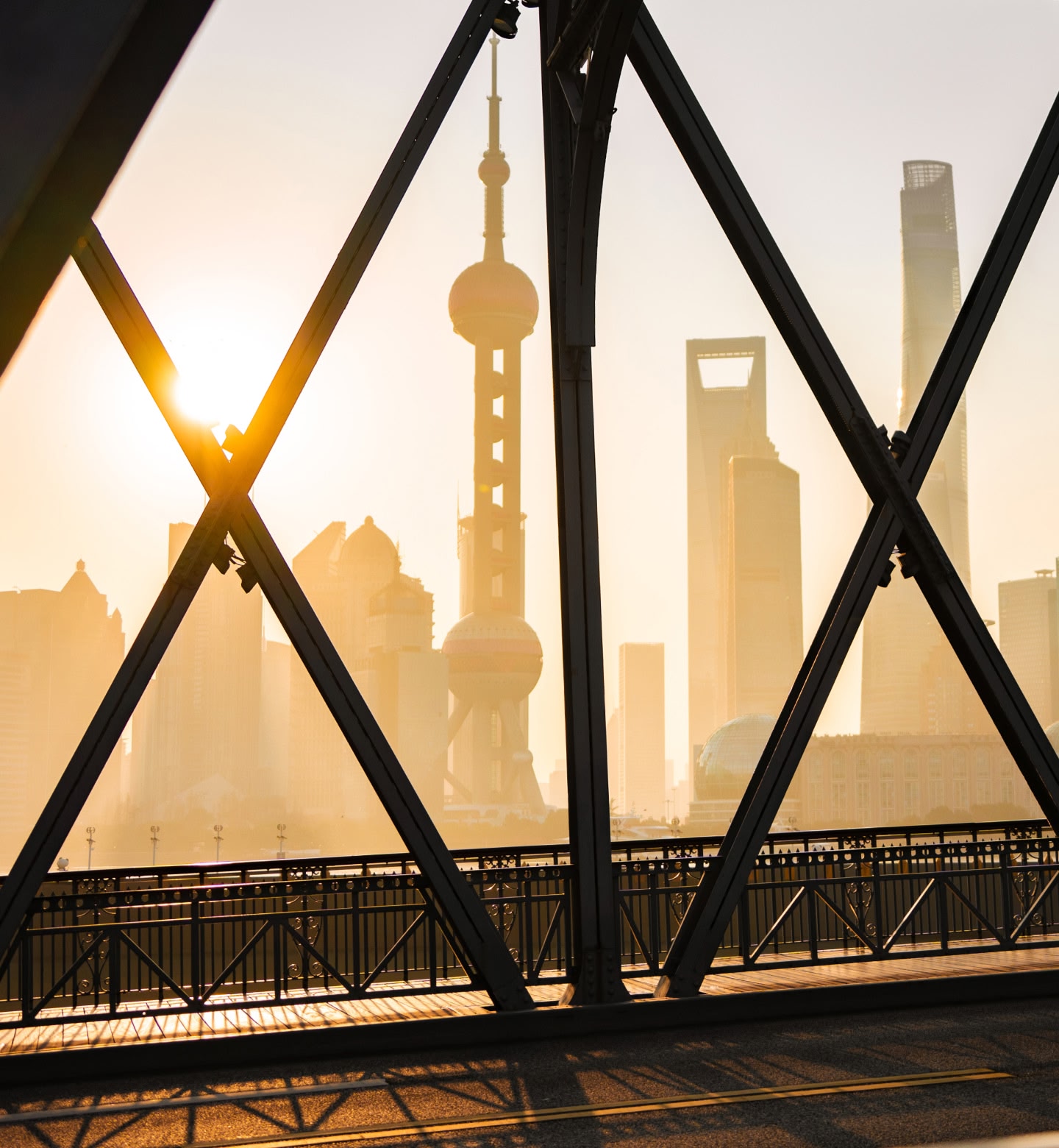 La ligne d'horizon de Shanghai vue à travers les poutres d'un pont au lever du soleil.
