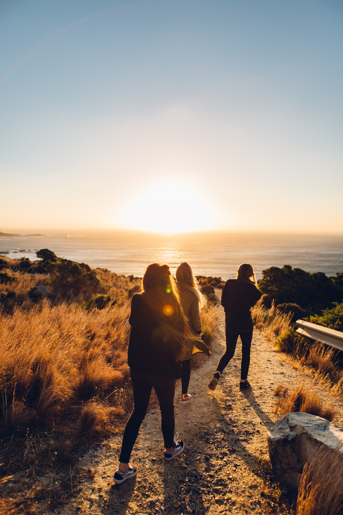 Three friends watch the sunset on the beach