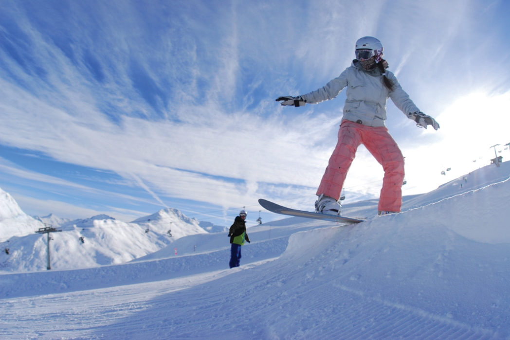 Γυναίκα που κάνει snowboard σε χιονισμένο βουνό.