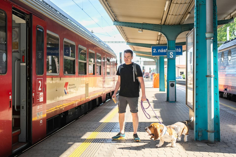 A photo of a man taking his dog on a train in Europe