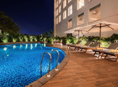 Mesmerizing view of a beautifully illuminated swimming pool at night, with the sparkling water reflecting the dazzling lights and creating a serene ambiance.