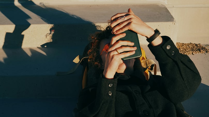 Frau liegt auf dem Boden und schaut auf ihr Smartphone