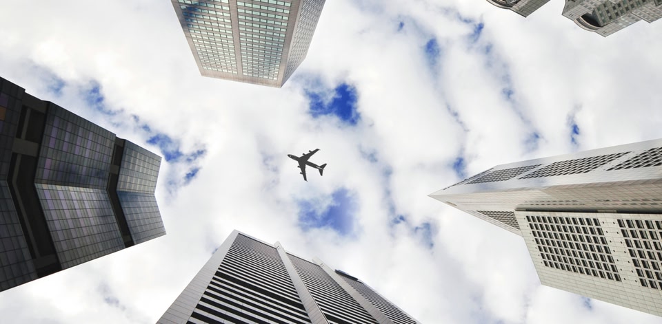Image of a plane in the sky flying over skyscrapers