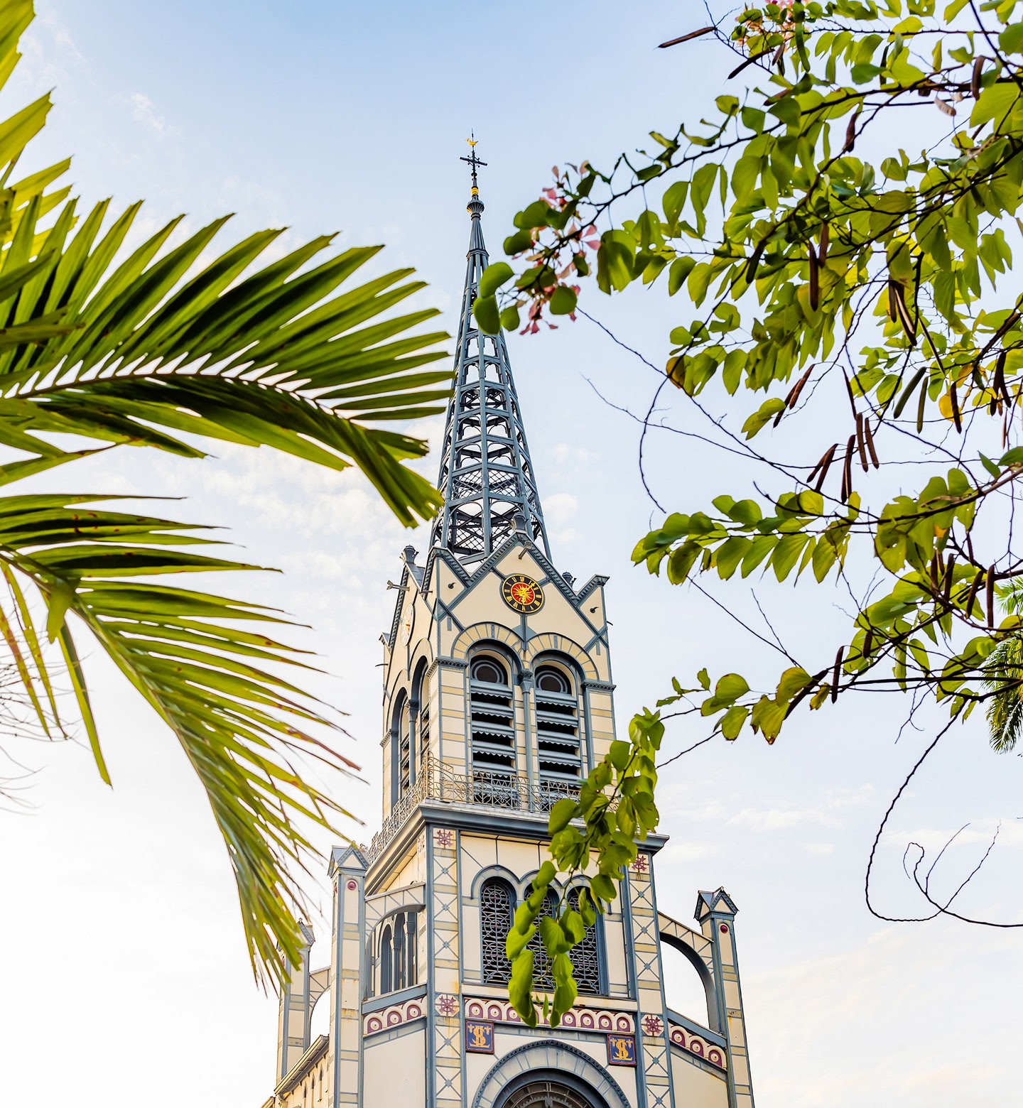 Ornate church tower framed by palm leaves under a pale evening sky in Fort-de-France, Martinique.