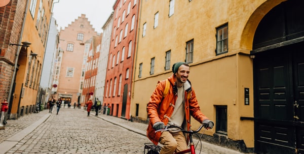 Person cycling down road in old part of European town with colourful yellow and orange buildings on either side of them.