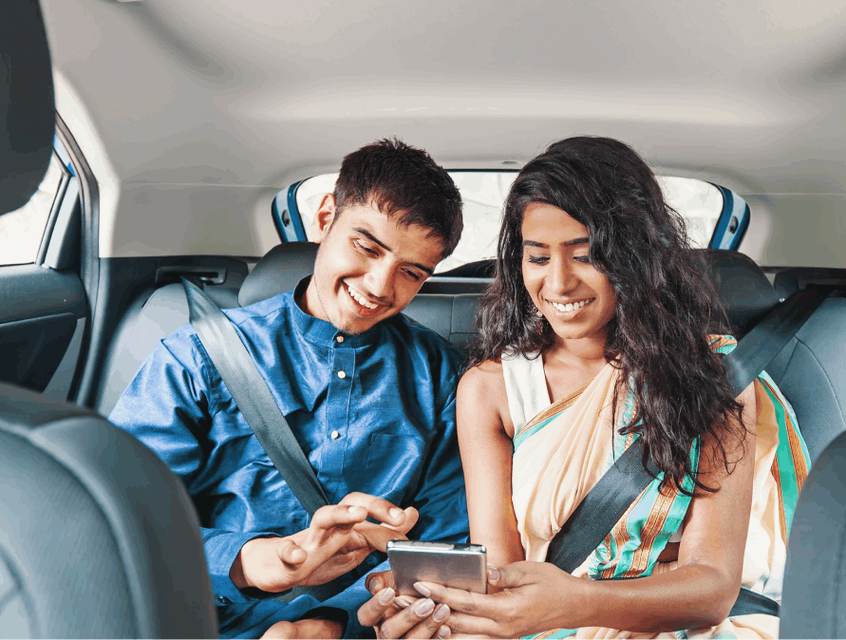 A happy couple checking their Skyscanner Da Nang travel guide in the back of a vehicle