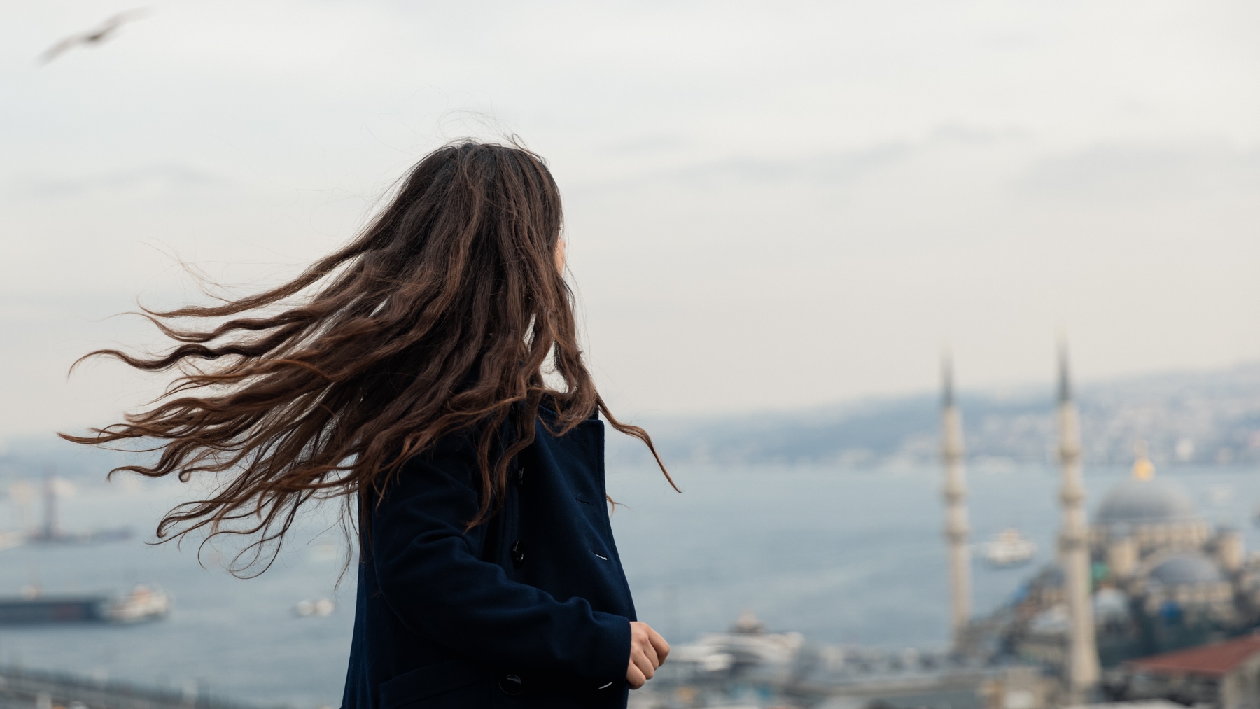 Young woman looking out over Istanbul, the wind whipping her hair.