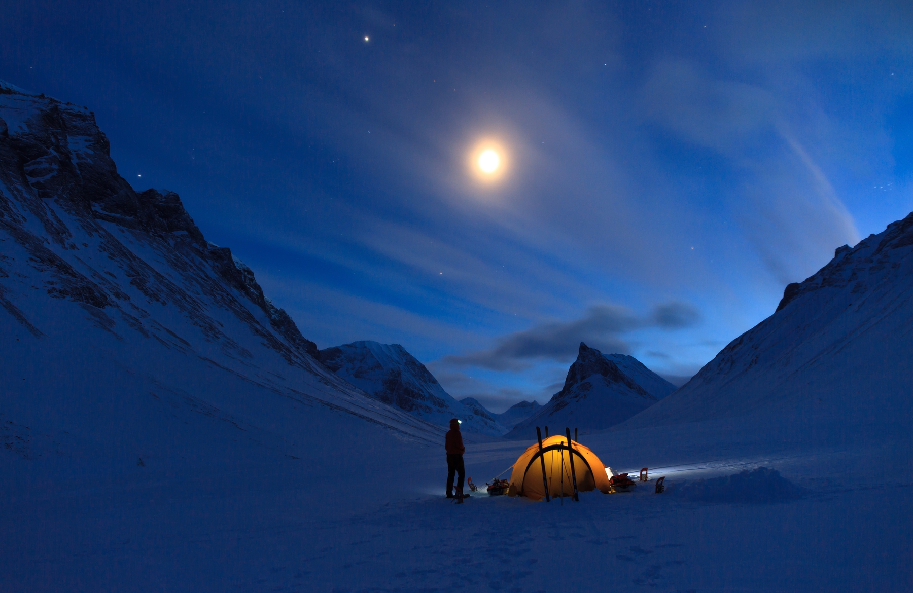 people setting up camp under the stars in the snowy mountains at night