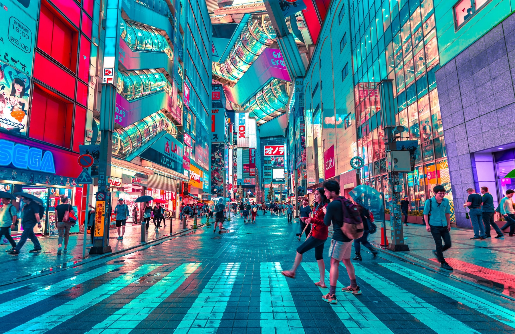 Tokyo's Akibahara district lit up at night, tourists walking along the roads.