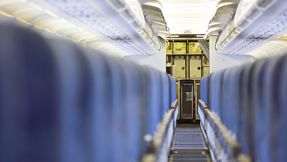 un corridoio interno di un aereo con sedili blu su entrambi i lati.