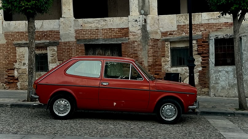 Auto d'epoca rossa parcheggiata su una strada acciottolata.