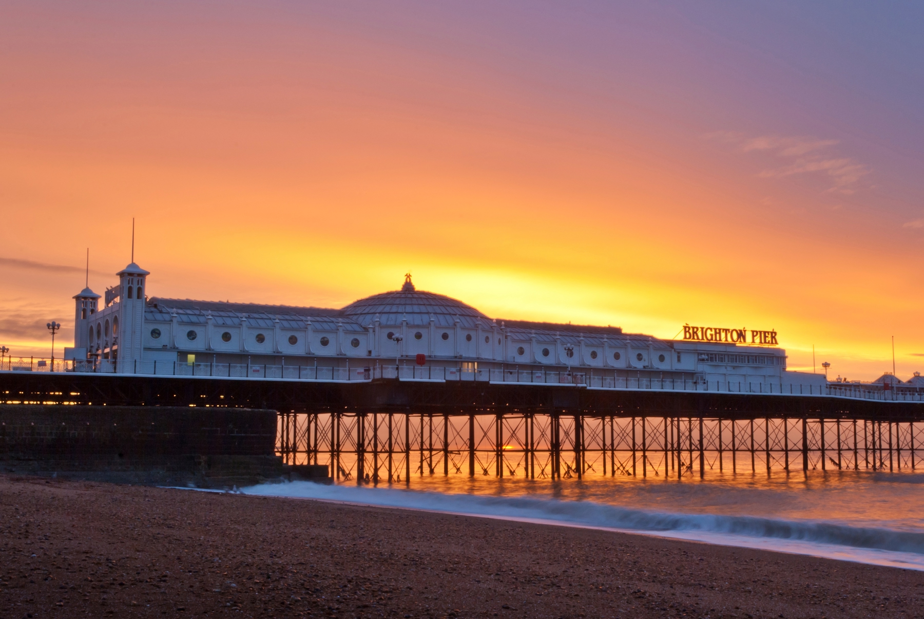 A view of Brighton pier from the beach at sunset