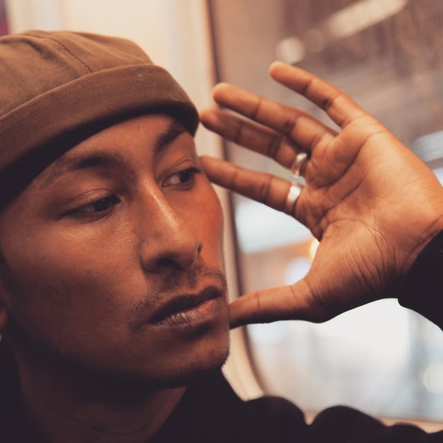 Singer Jitwam looking down with his hand to his head 