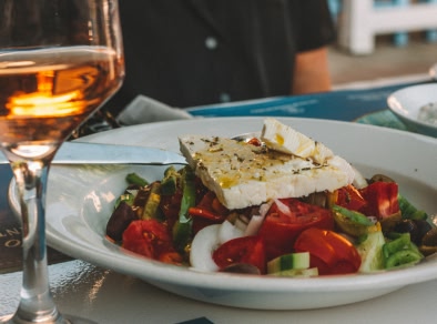 An image with typical Santorini food, sliced tomatoes, cucumbers, salad and feta cheese.