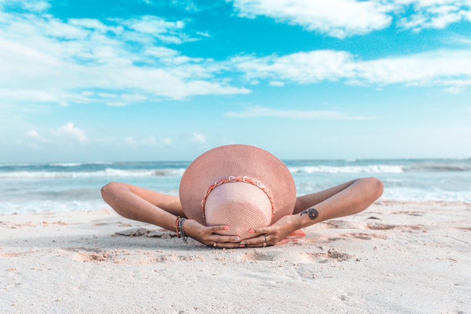 Woman in a sunhat relaxing on the white sand beaches of Playa del Carmen