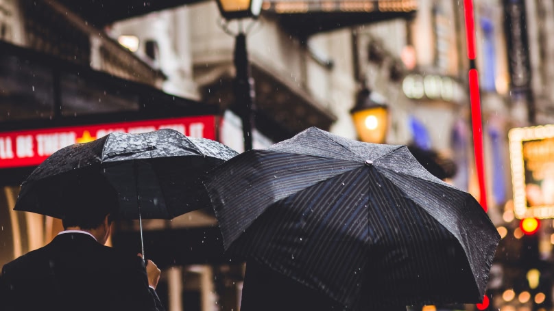 Deux personnes avec des parapluies noirs marchent sous la pluie