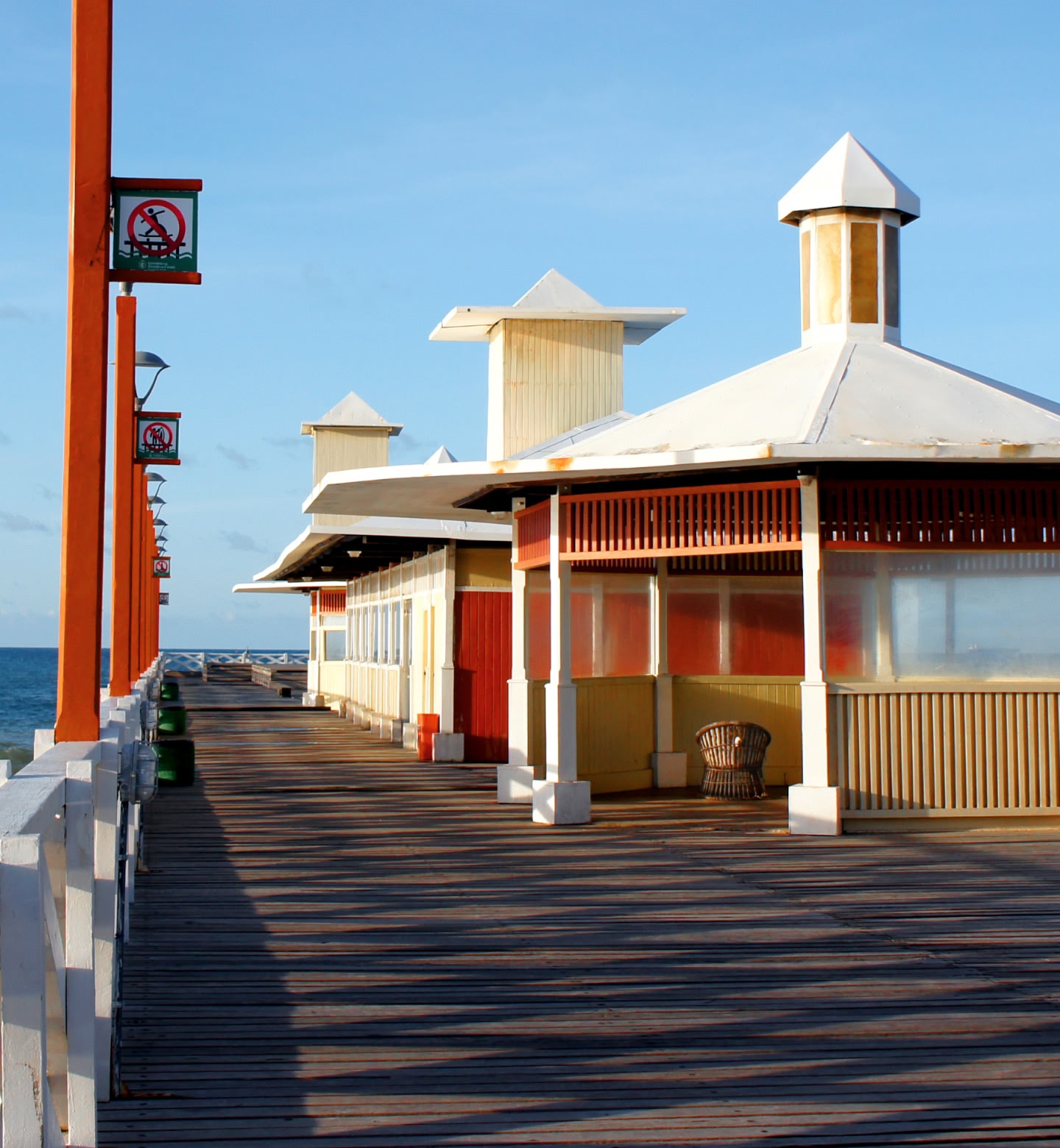 Um colorido píer à beira-mar com tábuas de madeira e barracas com telhados brancos em Fortaleza, Brasil.