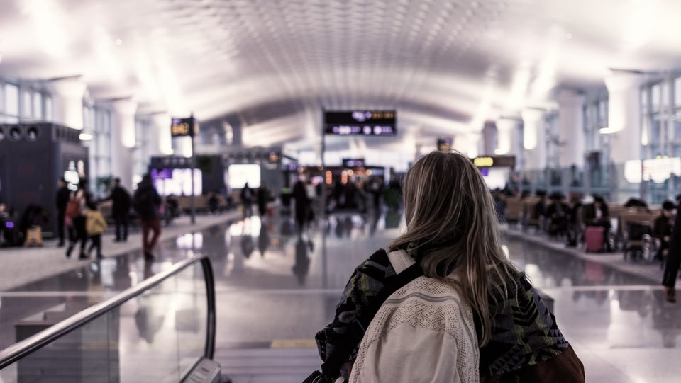 Une femme portant un sac à dos dans un terminal d'aéroport.