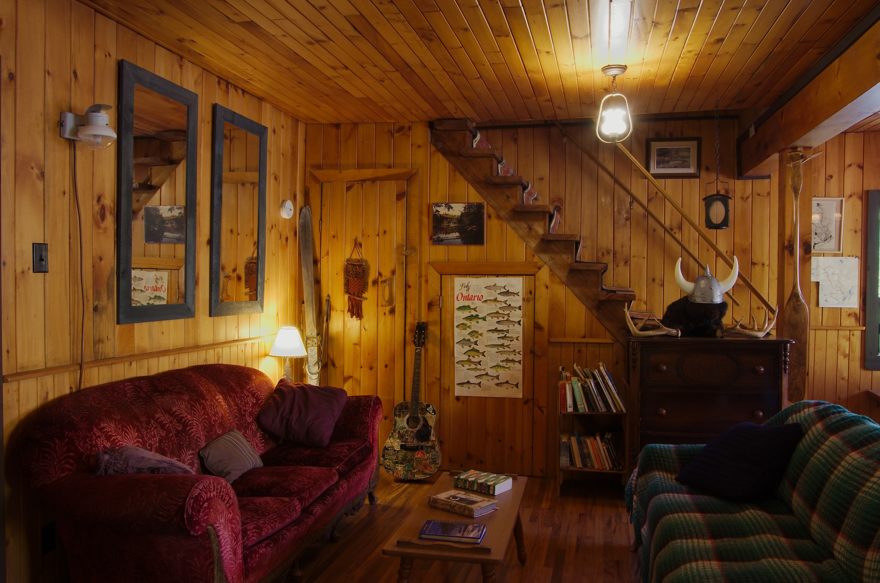 interior of algonquin eco lodge. a cozy living room with red couch, stairs, posters on wall