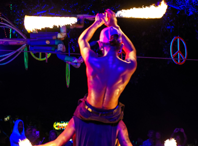 Ein fesselnder Blick hinter die Kulissen eines erfahrenen Künstlers auf einer lebendigen und farbenfrohen Bühne, der einen feurigen Taktstock über seinem Kopf schwingt.