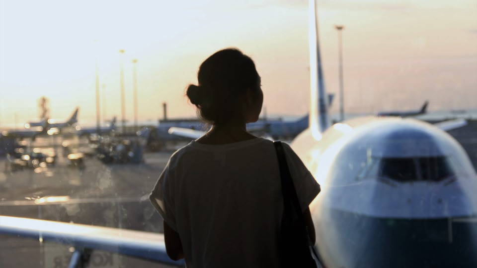 Silhouette of person looking out of an airport window at plane 