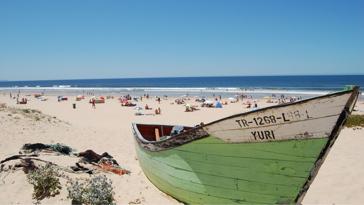 Une photo en gros plan d'un bateau de pêche sur une plage touristique bondée