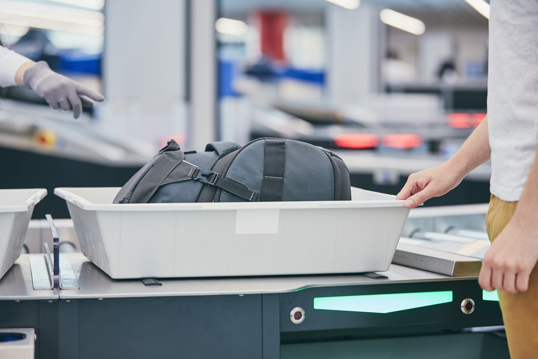 Young man (traveler) waiting for x-ray control his luggage.