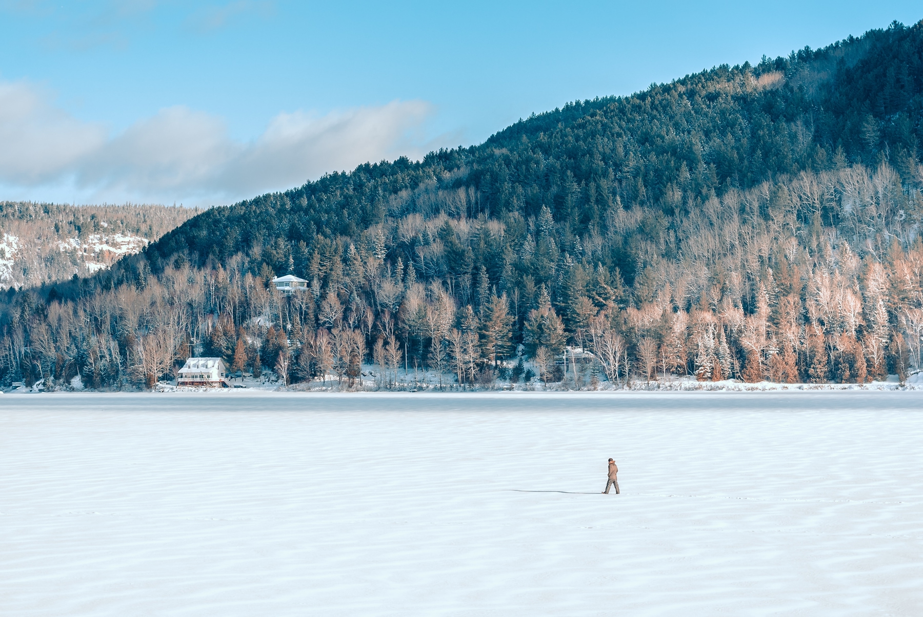 person walking on a frozen lake in Mont Tremblant, Quebec, on a sunny winter's day