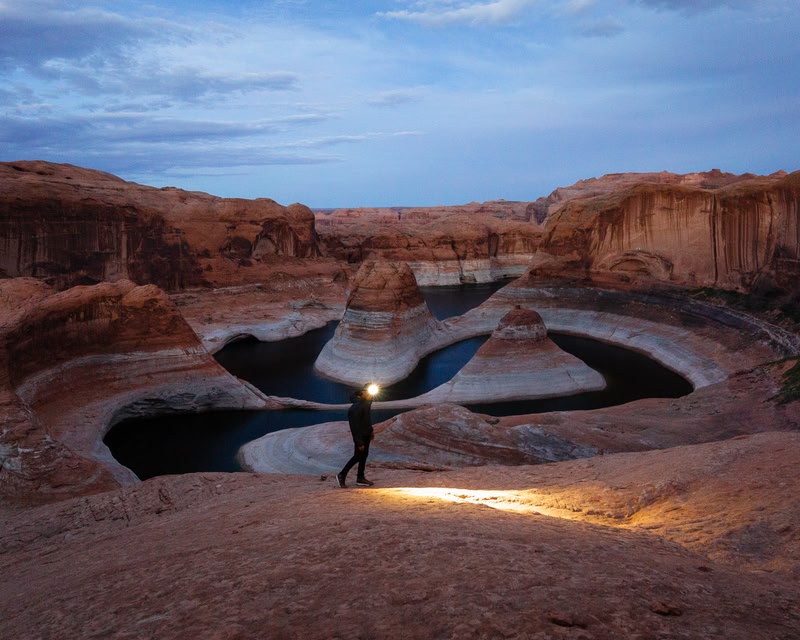 Photo of a hiker with a head torch taking a night hike overlooking Lake Powell, Grand Canyon