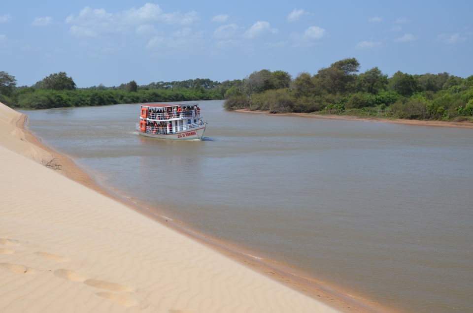 Barco visto a partir de dunas no delta do Parnaíba, destino para viajar em casal