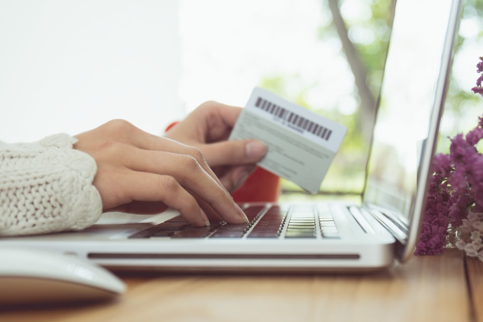 mãos femininas em um notebook com um cartão de crédito em mãos - formas de pagamento de passagens aéreas