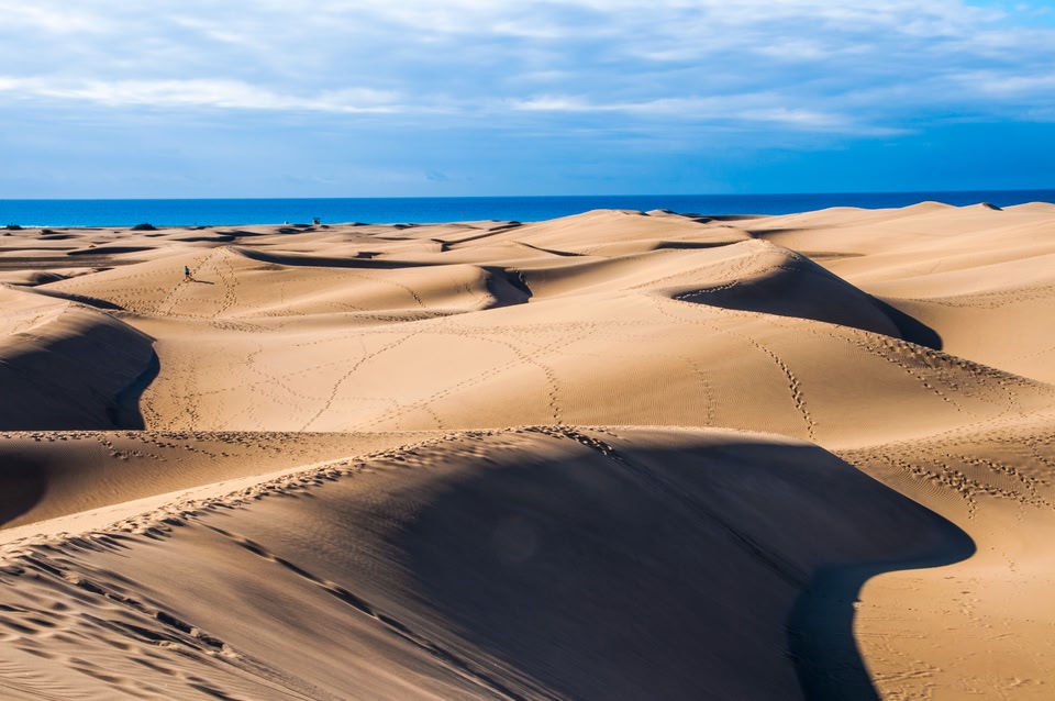 The rolling orange sands of Maspalomas dunes, running down to the deep blue of the ocean.