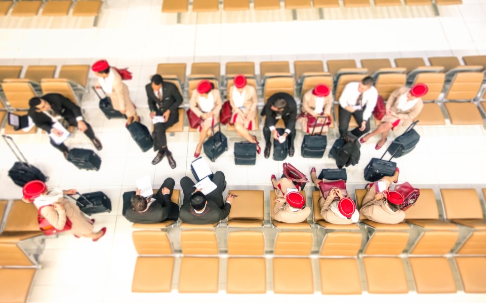 Hostesses and stewards top view at departures gate ready to flight at international airport - Airline company crew sitting before embark on plane - Radial zoom defocusing with focus on low right side
