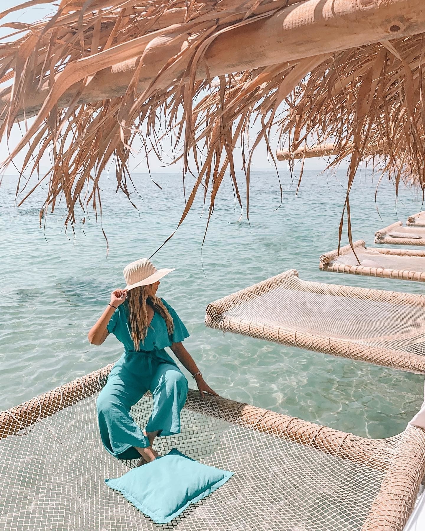 Young woman in a hat sitting on a mermaid net on a beach in Kasmil, Albania. 