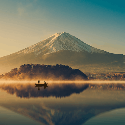 A cinematic picture of Mount Fuji which shows an atmospheric lake in the foreground with a single fishing boat floating on it and the imposing and majestic Mt Fuji towering up into the sky in the distance.