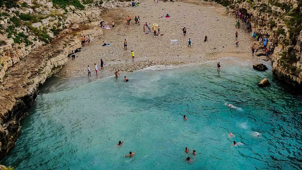 Vista aerea di una spiaggia affollata con acqua turchese.