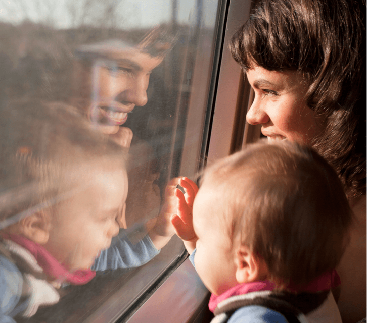 Adult and child sitting on a train looking out of the window. 