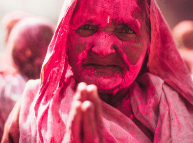 Old woman with a face covered in pink powder from Holi festival