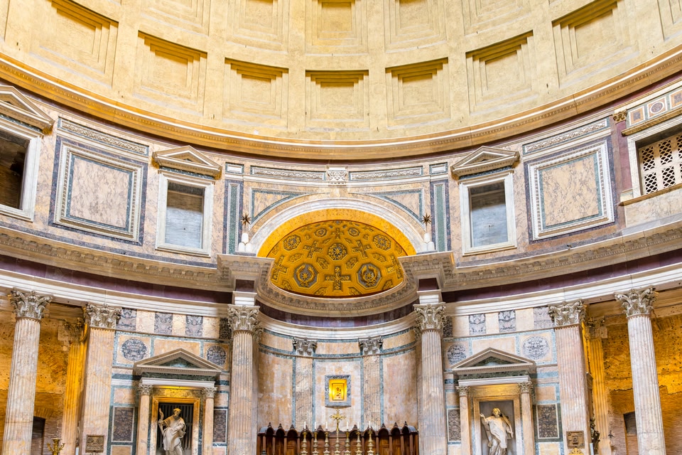 Ornate altar and coffered dome inside the Pantheon with marble columns.