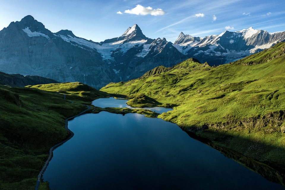 River flanked by green rolling hills with mountains in the background