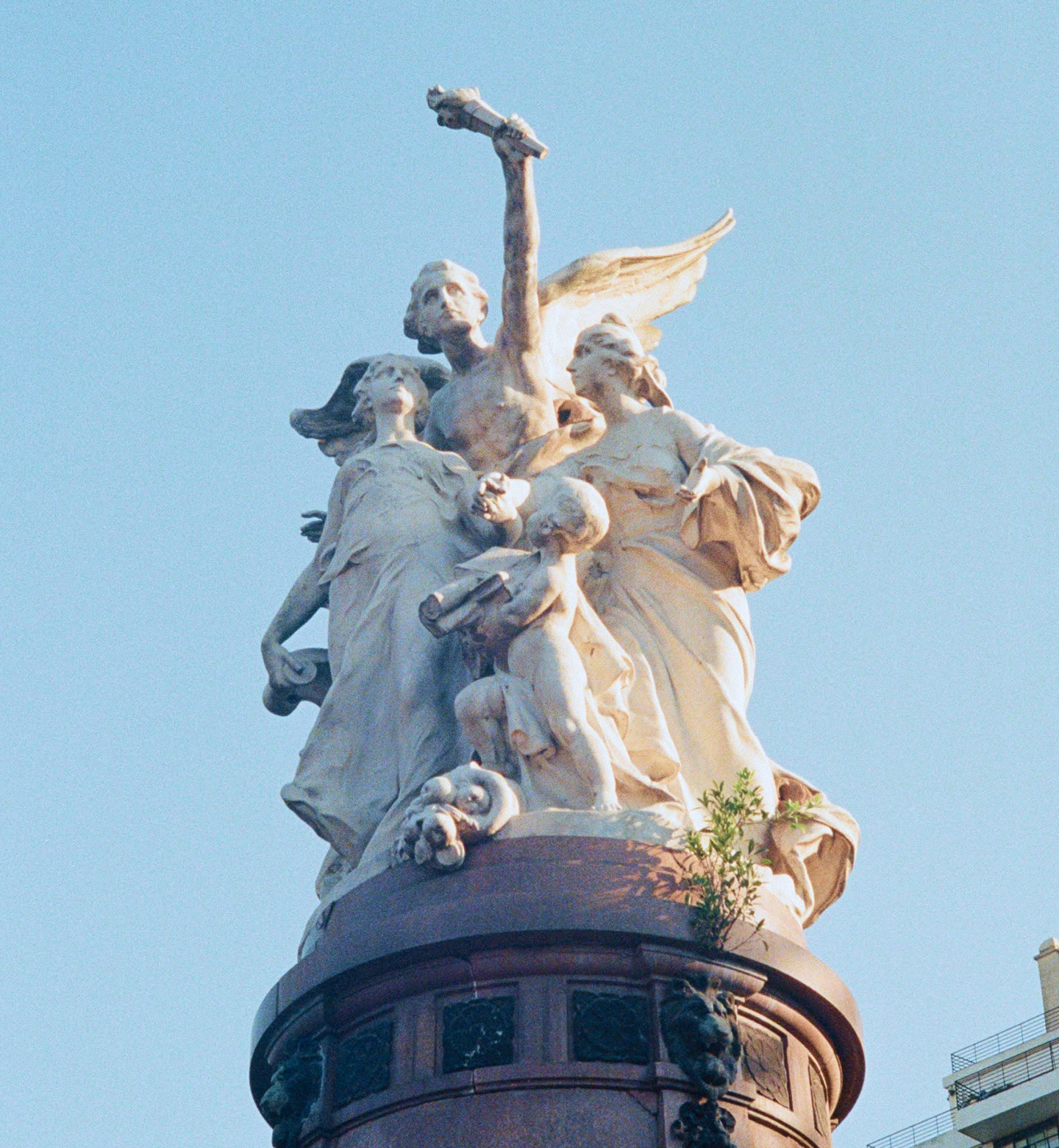 Primer plano de una escultura de mármol ornamentada en Buenos Aires, Argentina, con un cielo azul claro.