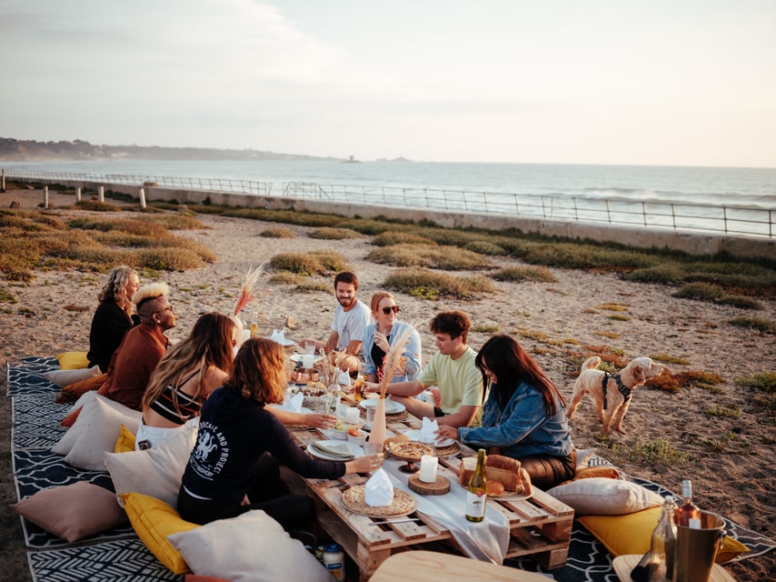 Group of friends gathering on a beach on Jersey t enjoy an al-fresco feast