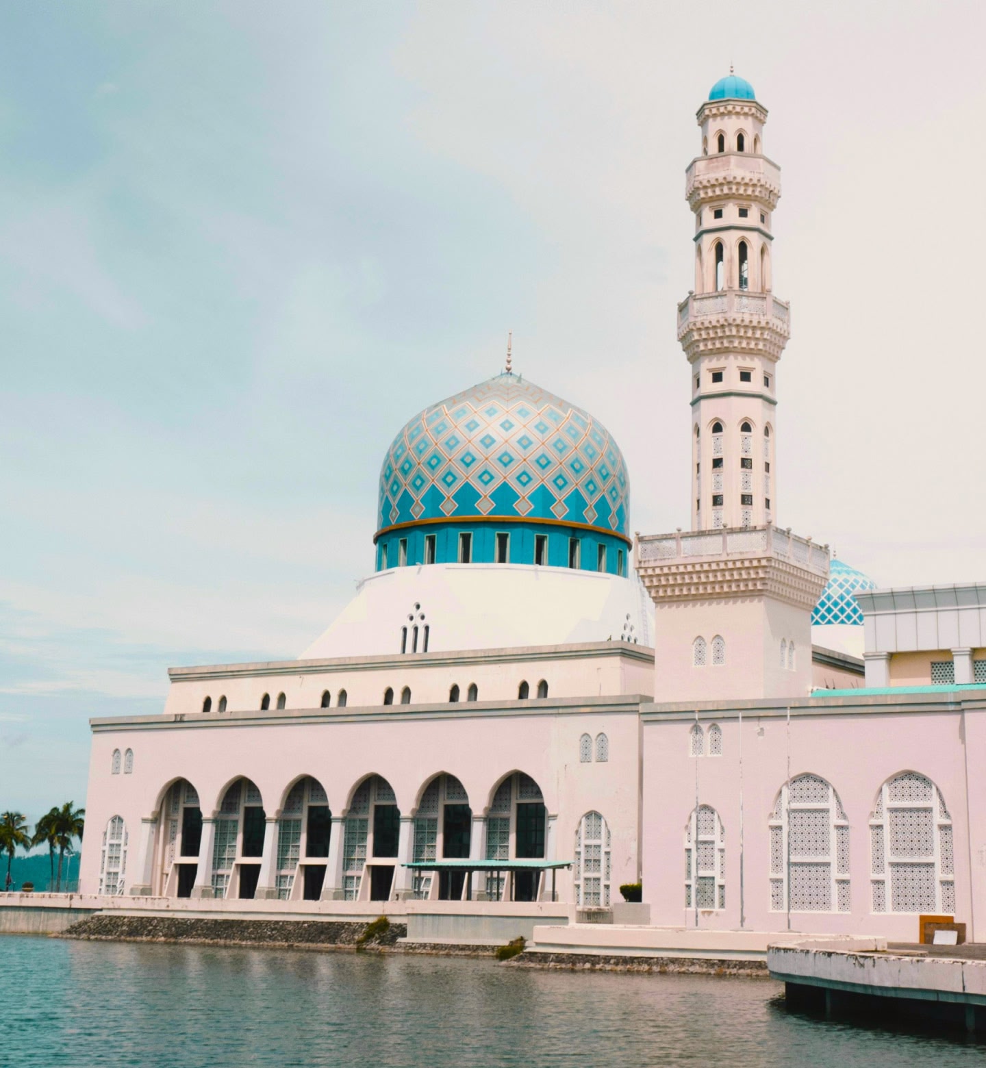 マレーシアのコタキナバルで、水面に映った模様のある青いドームとミナレットのあるモスク。