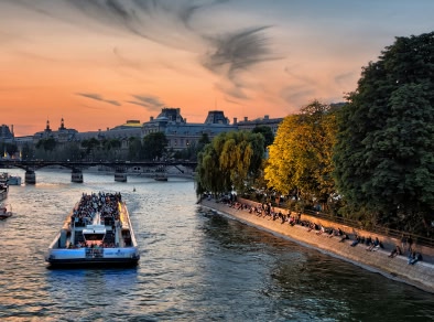 Un'immagine di una crociera fluviale a cielo aperto che attraversa la città con edifici storici in vista