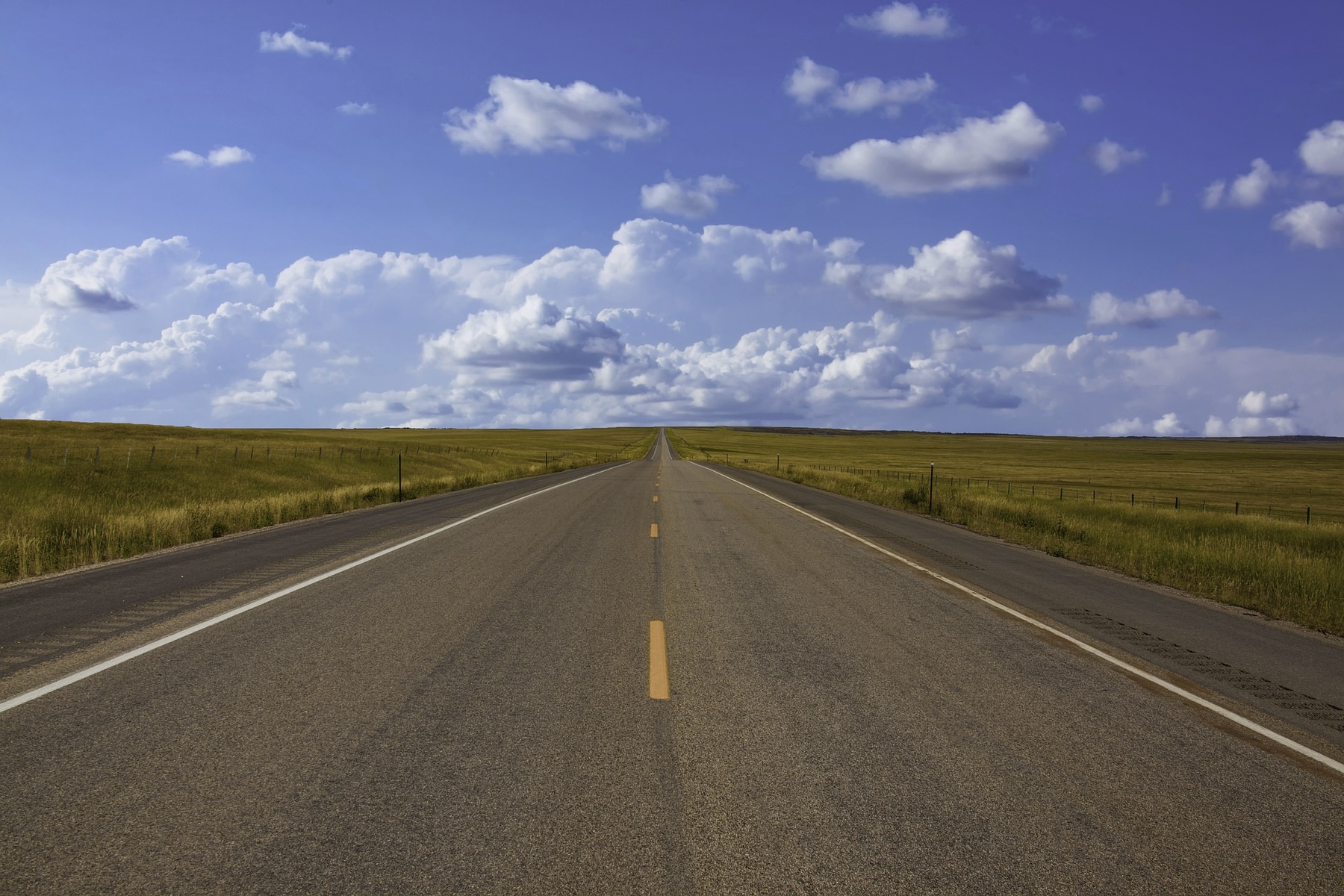 Long stretch of an empty highway with clouds on the horizon