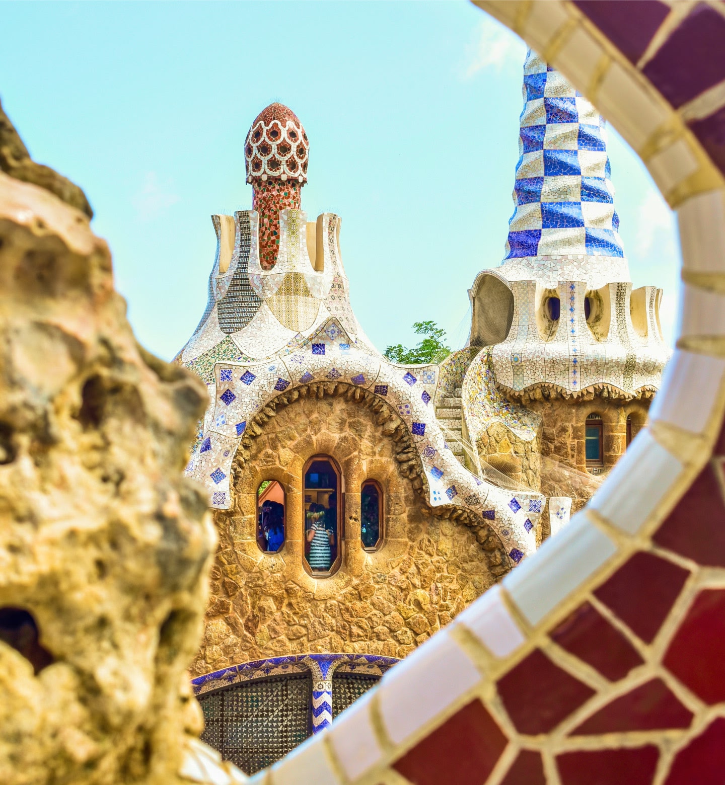 Las torres de mosaicos de Gaudí enmarcadas por piedras curvadas en Barcelona.