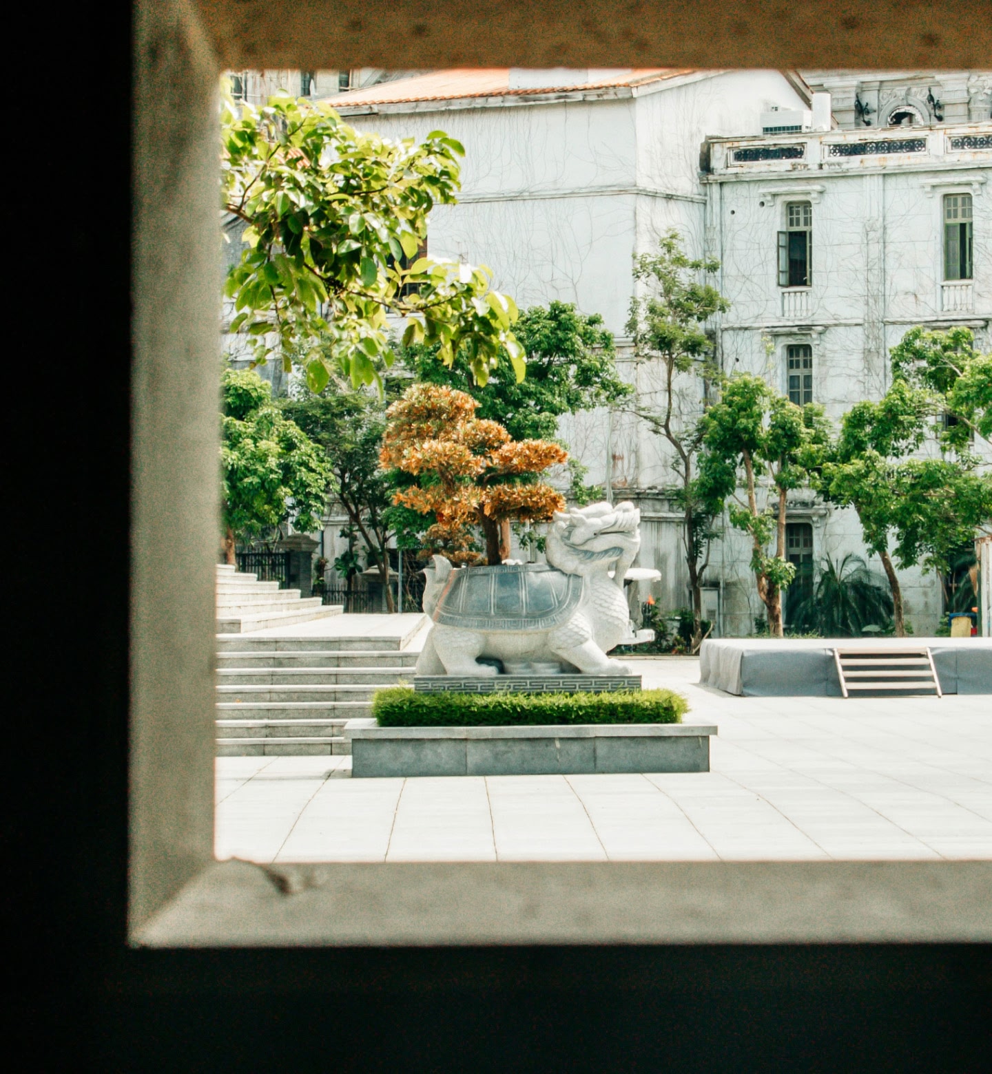 A courtyard with a dragon-turtle statue framed by trees and buildings in Harbin, China.