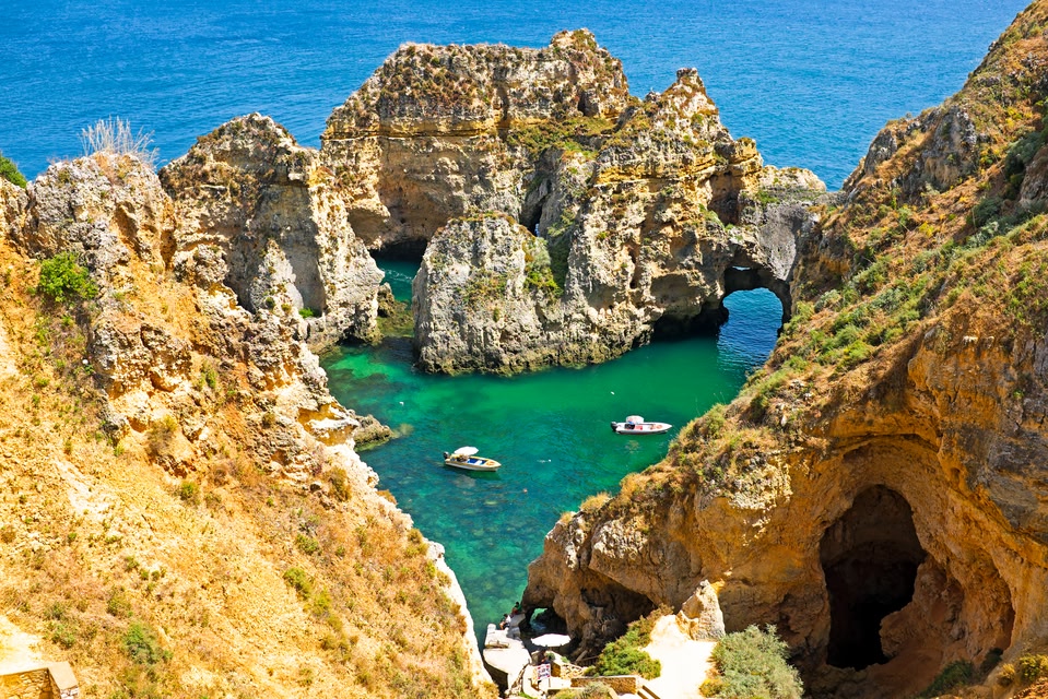 Boats sailing amongst the rugged cliffs of the Algarve coast.